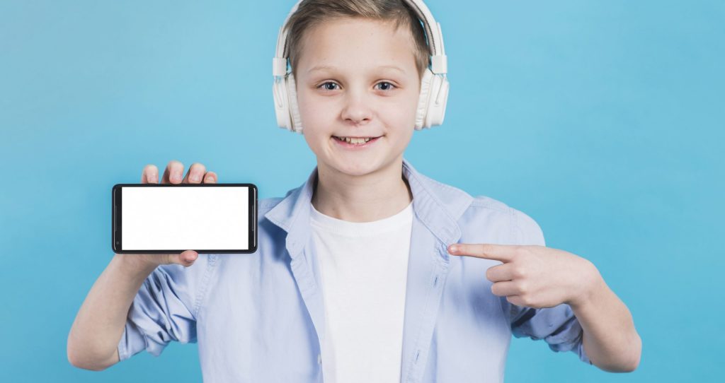 close-up-boy-wearing-headphone-head-pointing-her-finger-toward-mobile-phone-with-blank-screen close-up-boy-wearing-headphone-head-pointing-her-finger-toward-mobile-phone-with-blank-screen